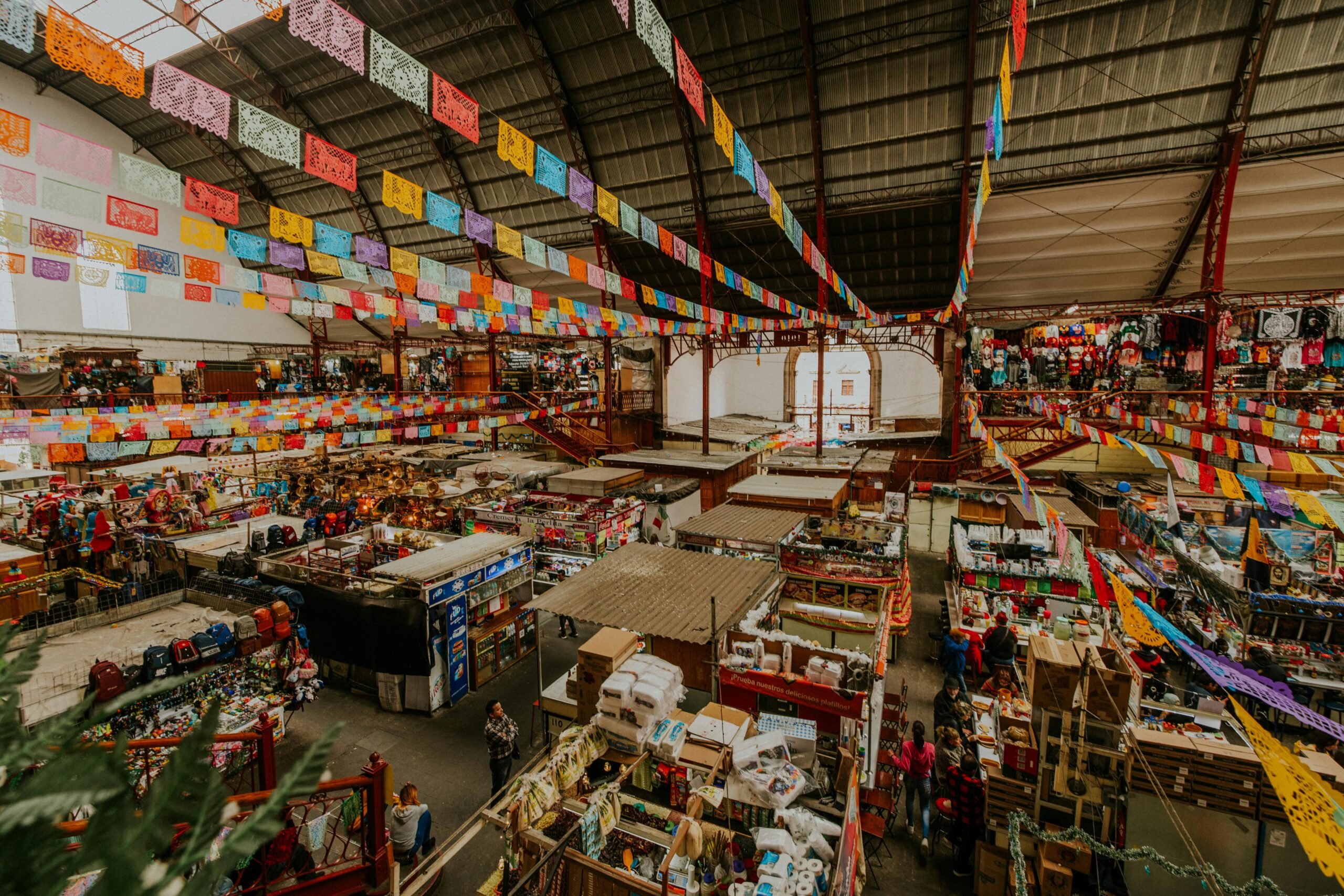 A bustling indoor market with colorful banners and diverse product stalls, capturing urban vibrancy.